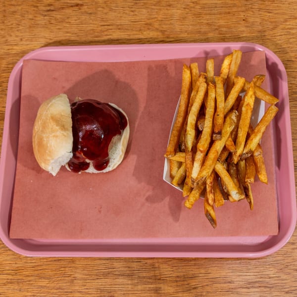 B&B BBQ slider with barbecue sauce and a side of golden french fries on a pink tray.