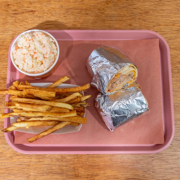 B&B BBQ burrito, fries, and coleslaw on a pink tray, on a wooden table.